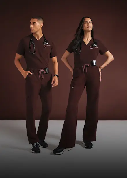 Two healthcare professionals wearing limited-edition FIGS Espresso scrubs, highlighting the surprise return of the viral colorway.