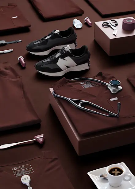 Flatlay of FIGS Espresso scrub top and pants with a stethoscope, highlighting the return of the limited-edition Espresso collection.