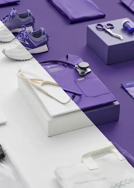 Flat lay of Optic White and Amethyst healthcare apparel and accessories, including scrubs, stethoscope, footwear, and socks.