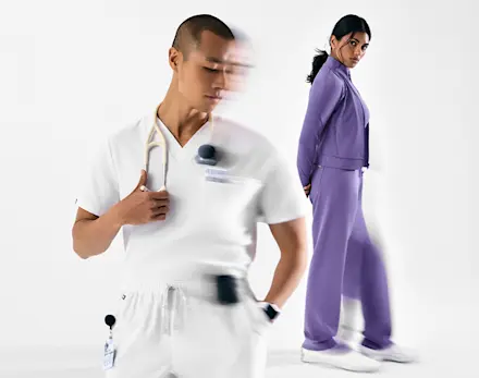 Healthcare professional wearing Optic White scrubs alongside healthcare professional wearing Amethyst purple scrubs.