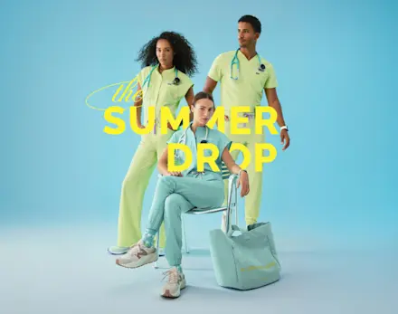 Three healthcare professionals wearing limited-edition Sea Mist and Seaglass FIGS scrubs pose together against a soft blue background for the Summer Drop collection.