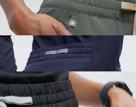 Healthcare professionals wearing FIGS scrubs in black, white, navy, moss, and gray stand together against a white background.